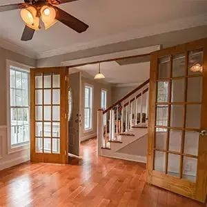 Bright kitchen under renovation with ladder, cabinets, tools, and a worker near the doorway