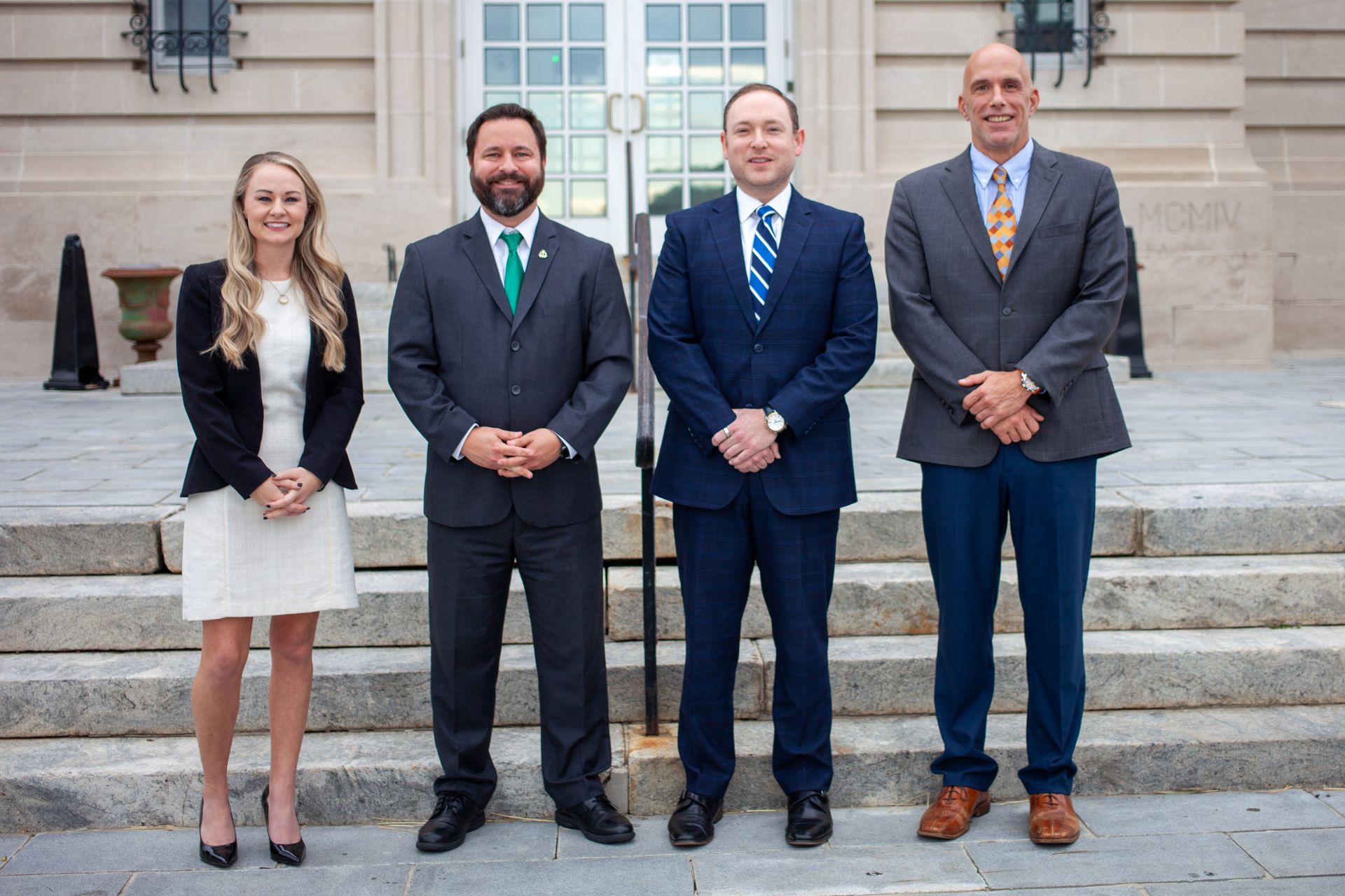 A group of people in suits and ties are posing for a picture in front of a building.