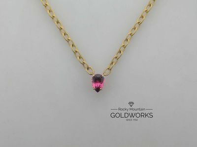 Gold chain necklace with a pink pendant on a white background, Goldworks logo below