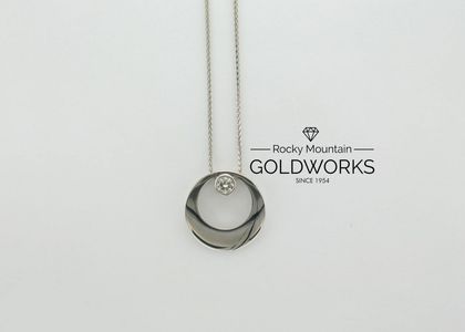 Silver pendant necklace beside Rocky Mountain Goldworks logo on a white background