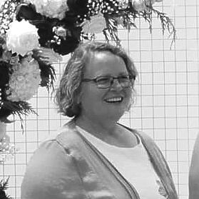 Licensed Senior Tech A woman wearing glasses is smiling in a black and white photo.