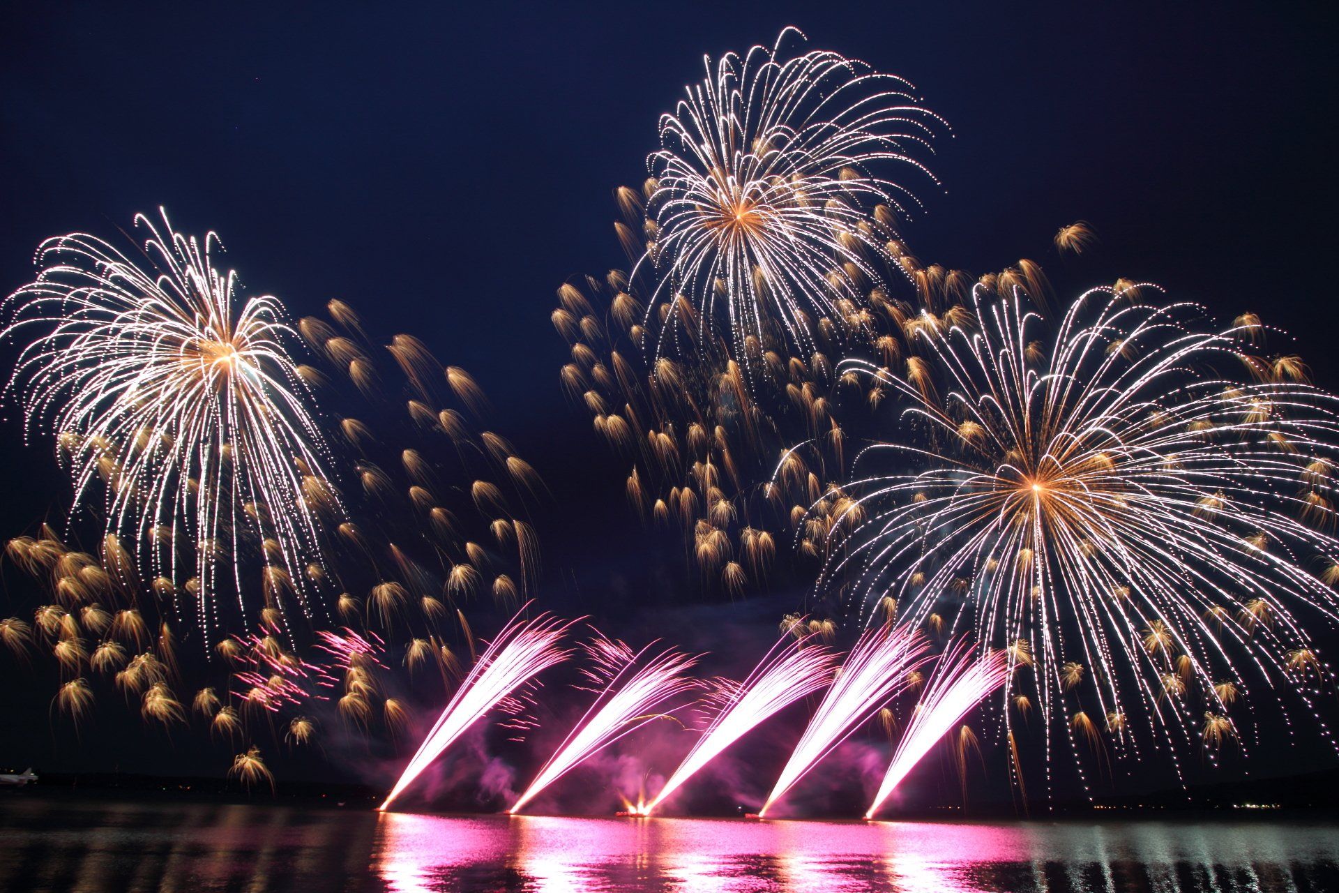 A bunch of fireworks are going off over a body of water