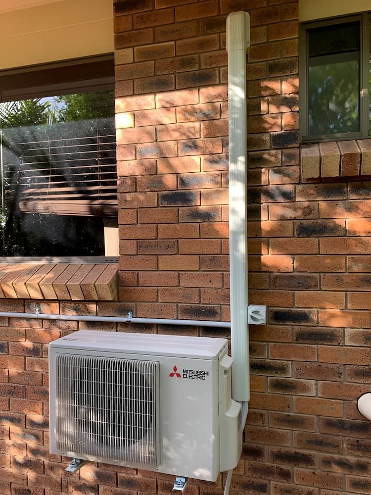 A Mitsubishi Air Conditioner Is Installed On The Side Of A Brick Building — Levi's Electrics in Emerald, QLD