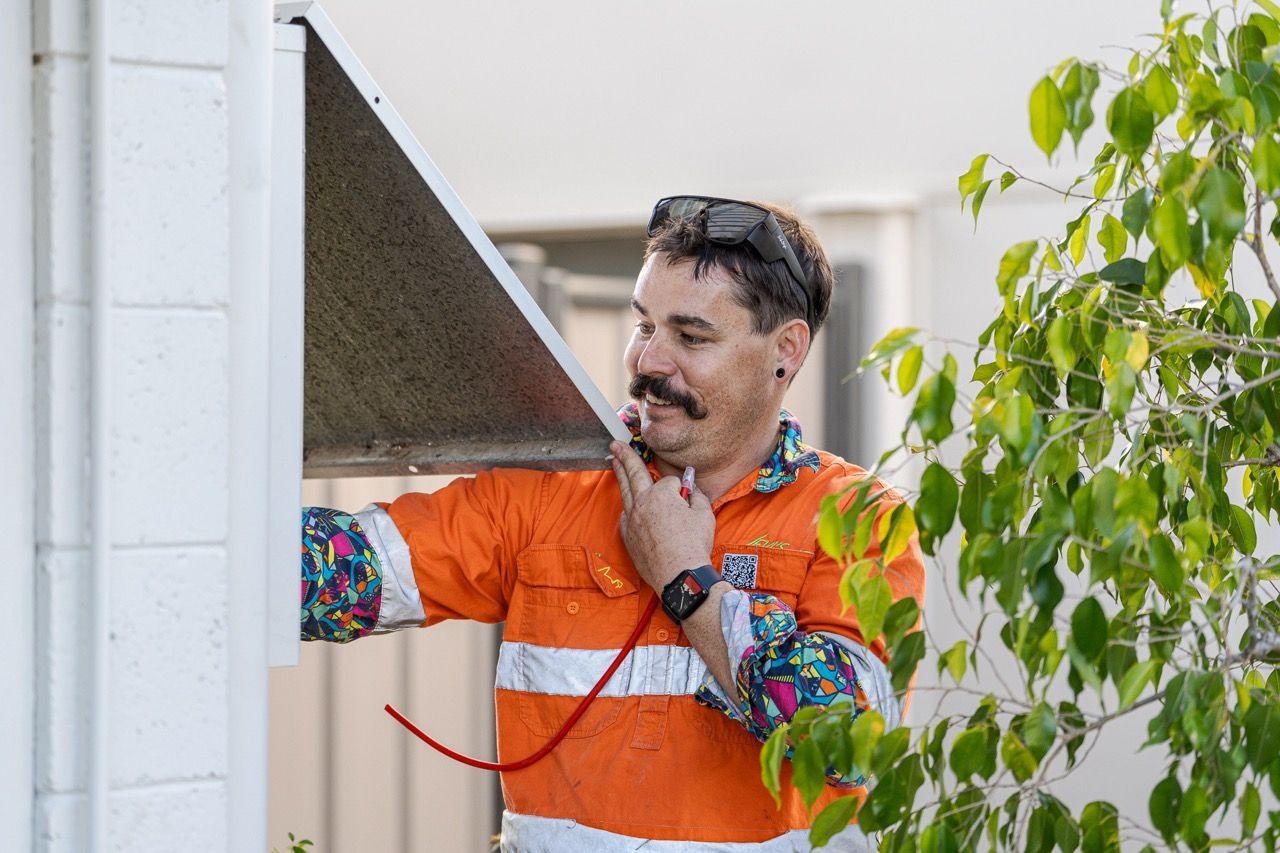 Levi Working On A Switchboard Box on a Building Wall — LV Energy Solutions in Nerimbera, QLD