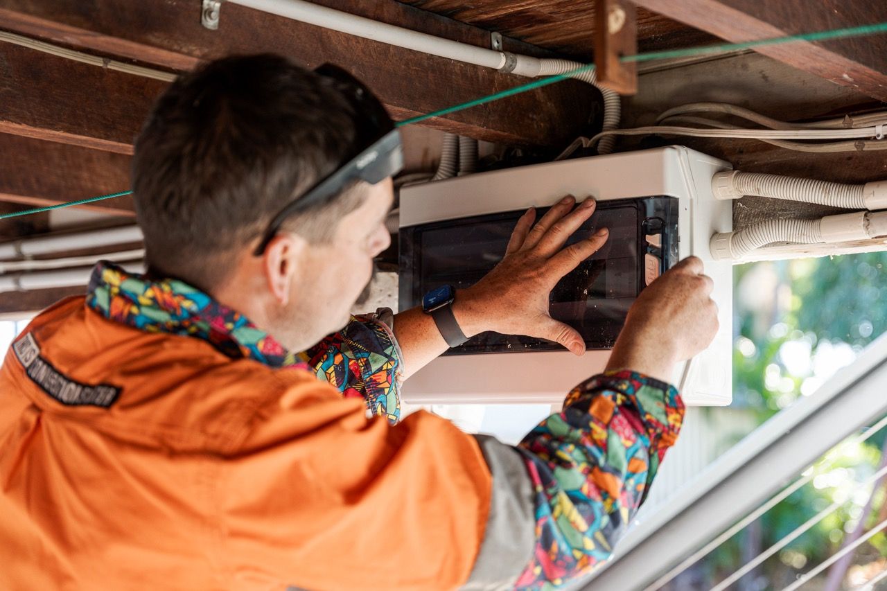Tradesman Working On An Electrical Box Under A Building — LV Energy Solutions in Nerimbera, QLD