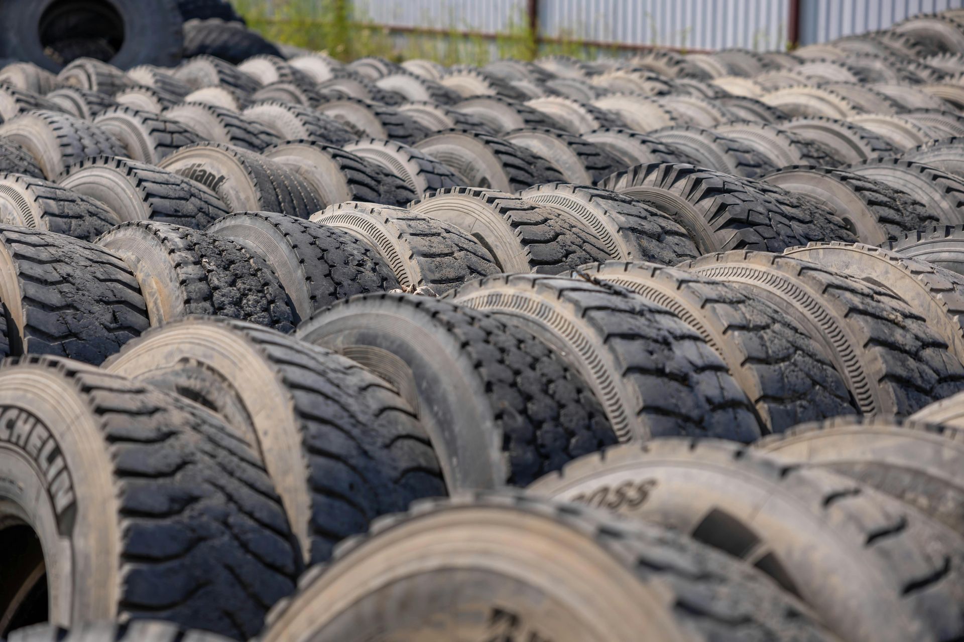 Stacks of used tires piled outdoors in a storage yard