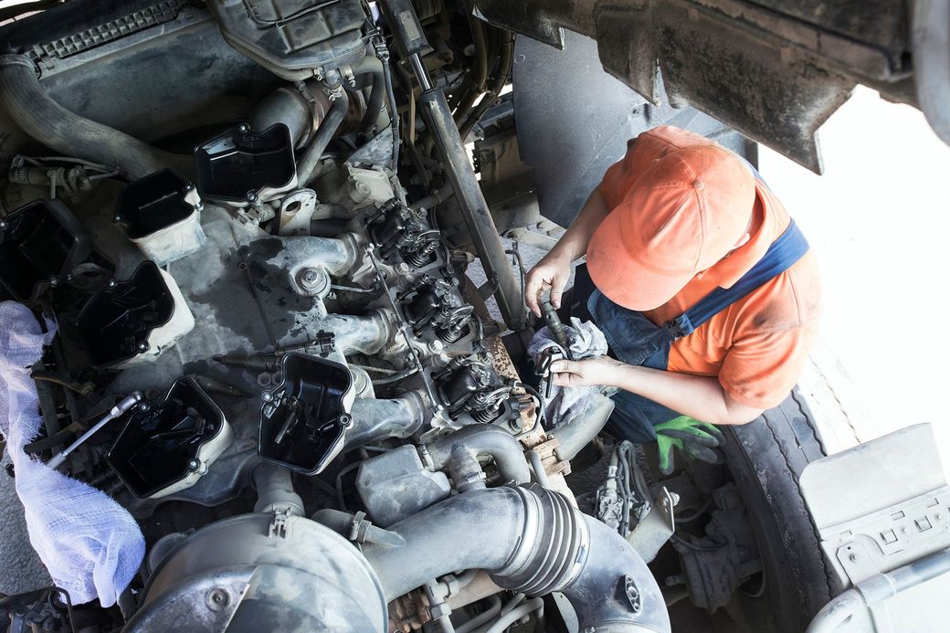 Worker in orange safety gear inspecting machinery in a cramped industrial engine room