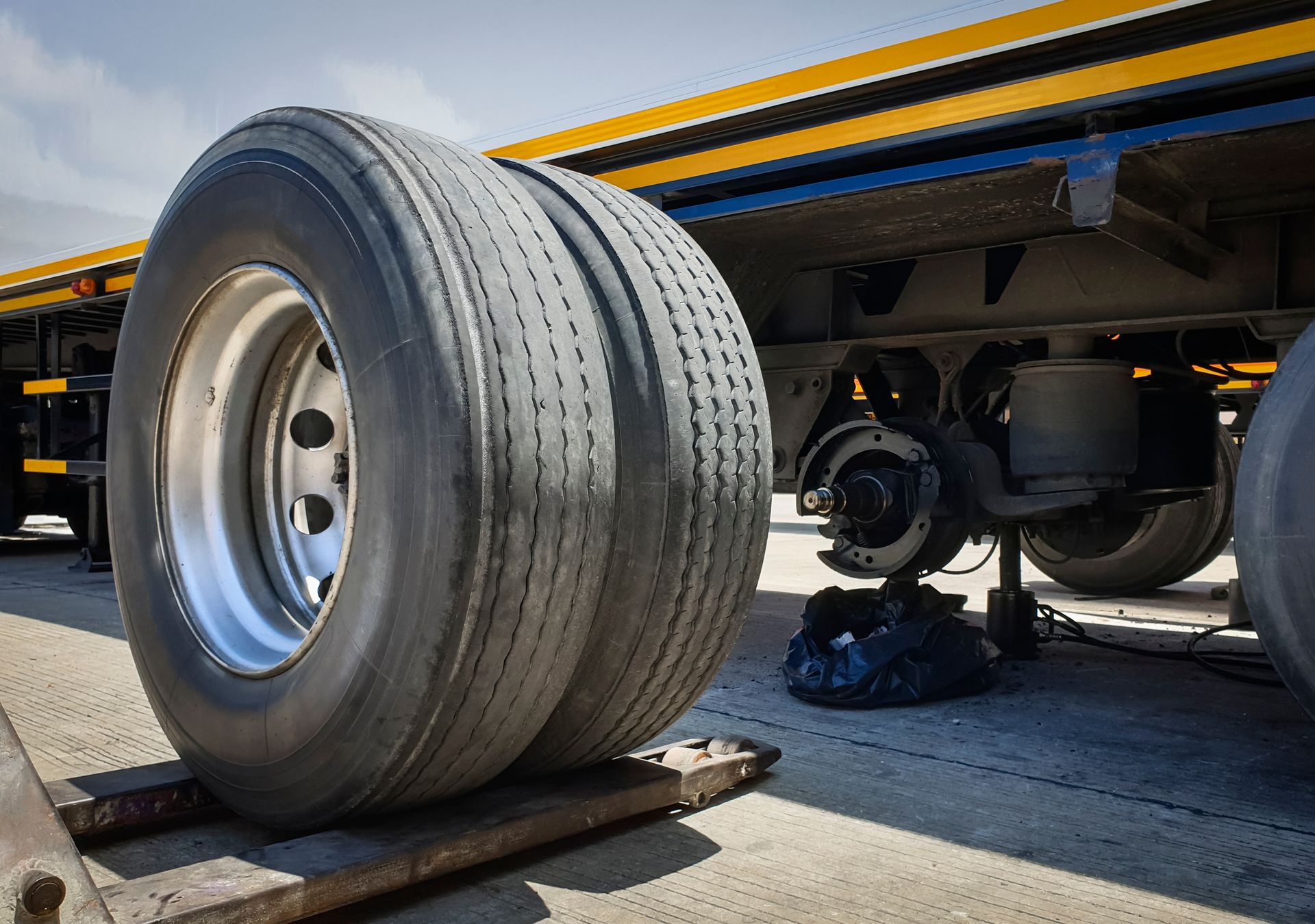 Close-up of a truck’s large rear tire on the roadside, with the undercarriage visible.