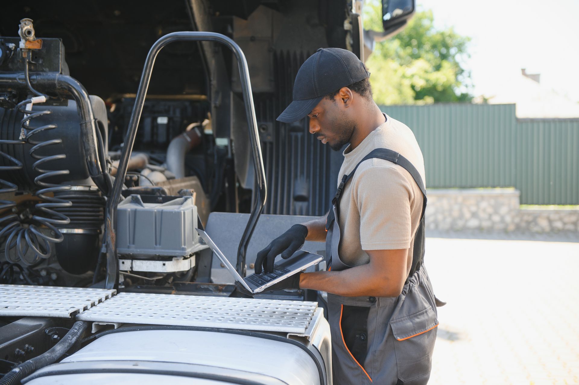 Worker in a tan shirt and cap inspecting equipment on a truck bed outdoors.