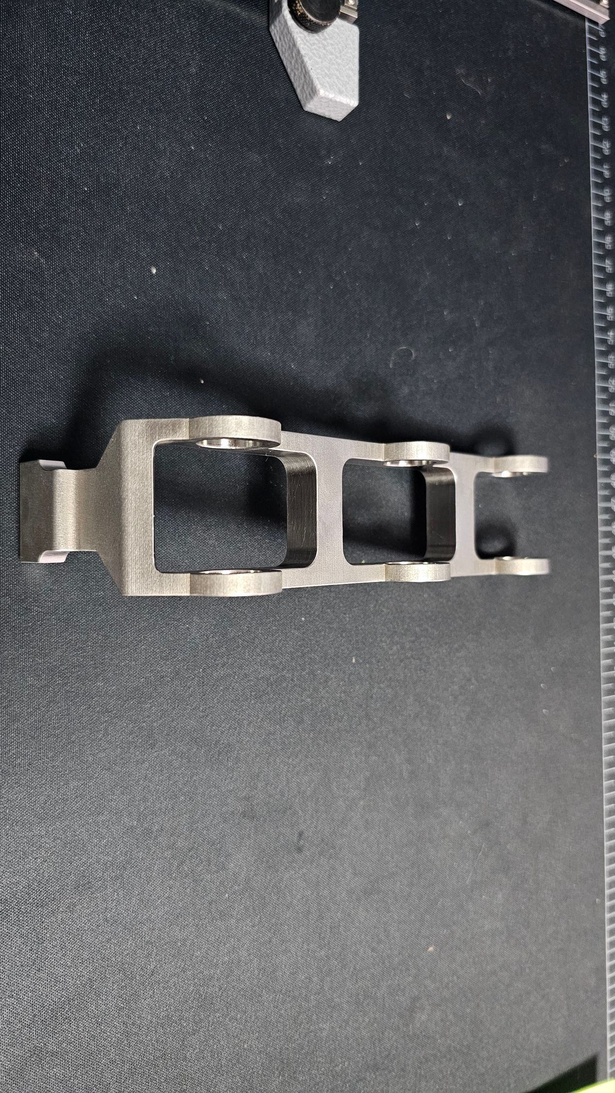 Small silver metal clip or buckle lying on dark fabric with a stitched edge