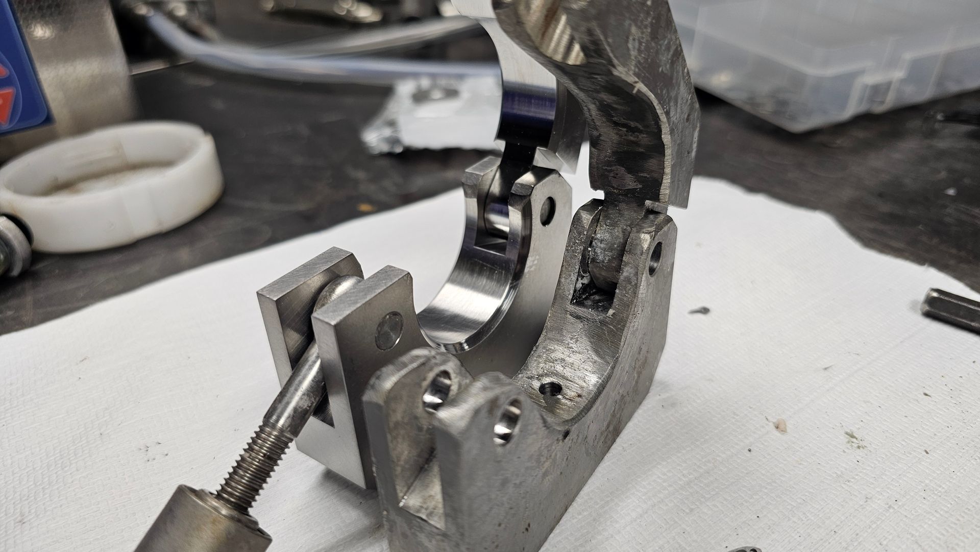 Metal mechanical part being clamped in a vise on a workbench, with a tool inserted for adjustment