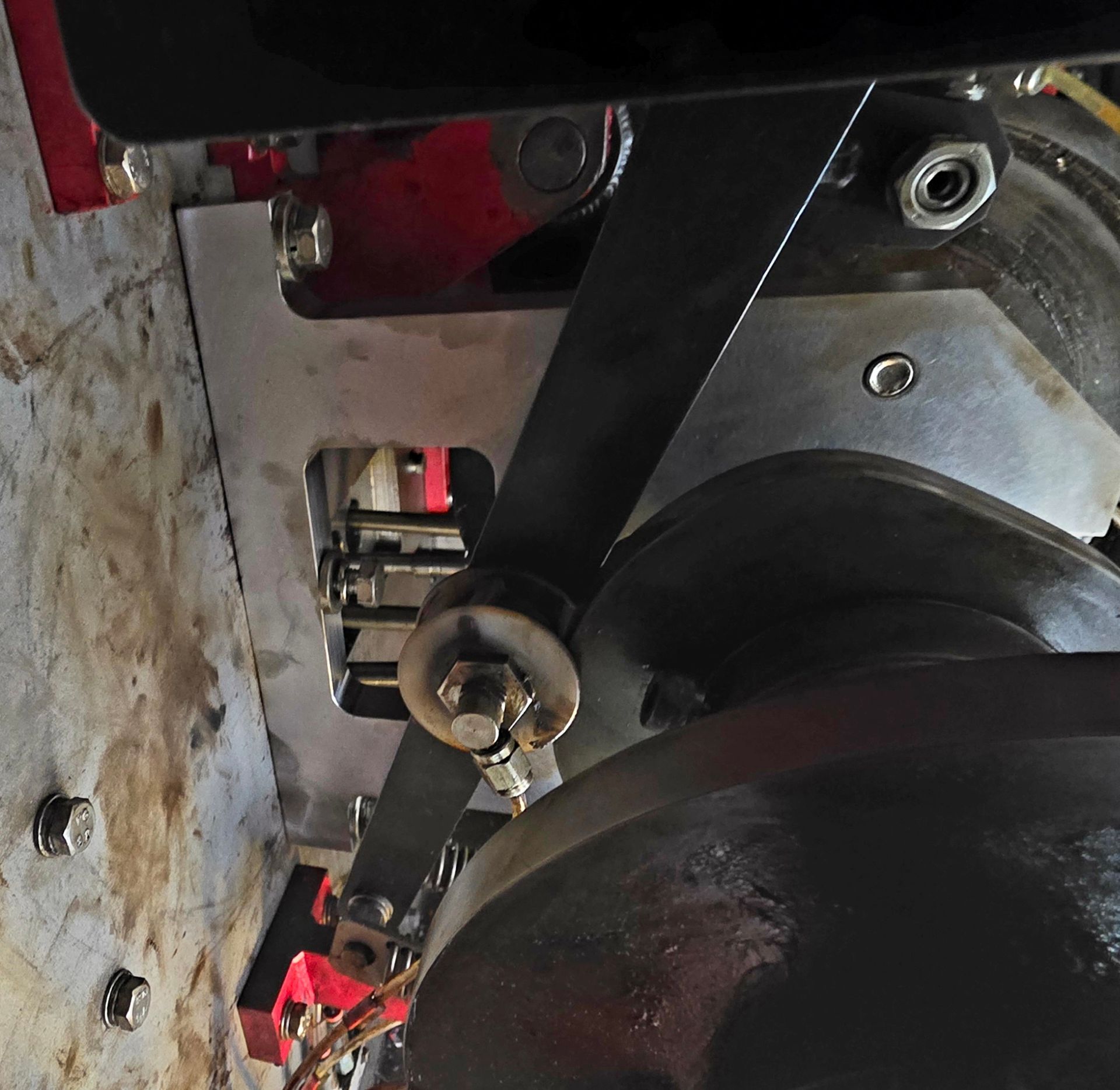 Close-up of a black belt and pulley mechanism on industrial machinery with red and silver metal parts