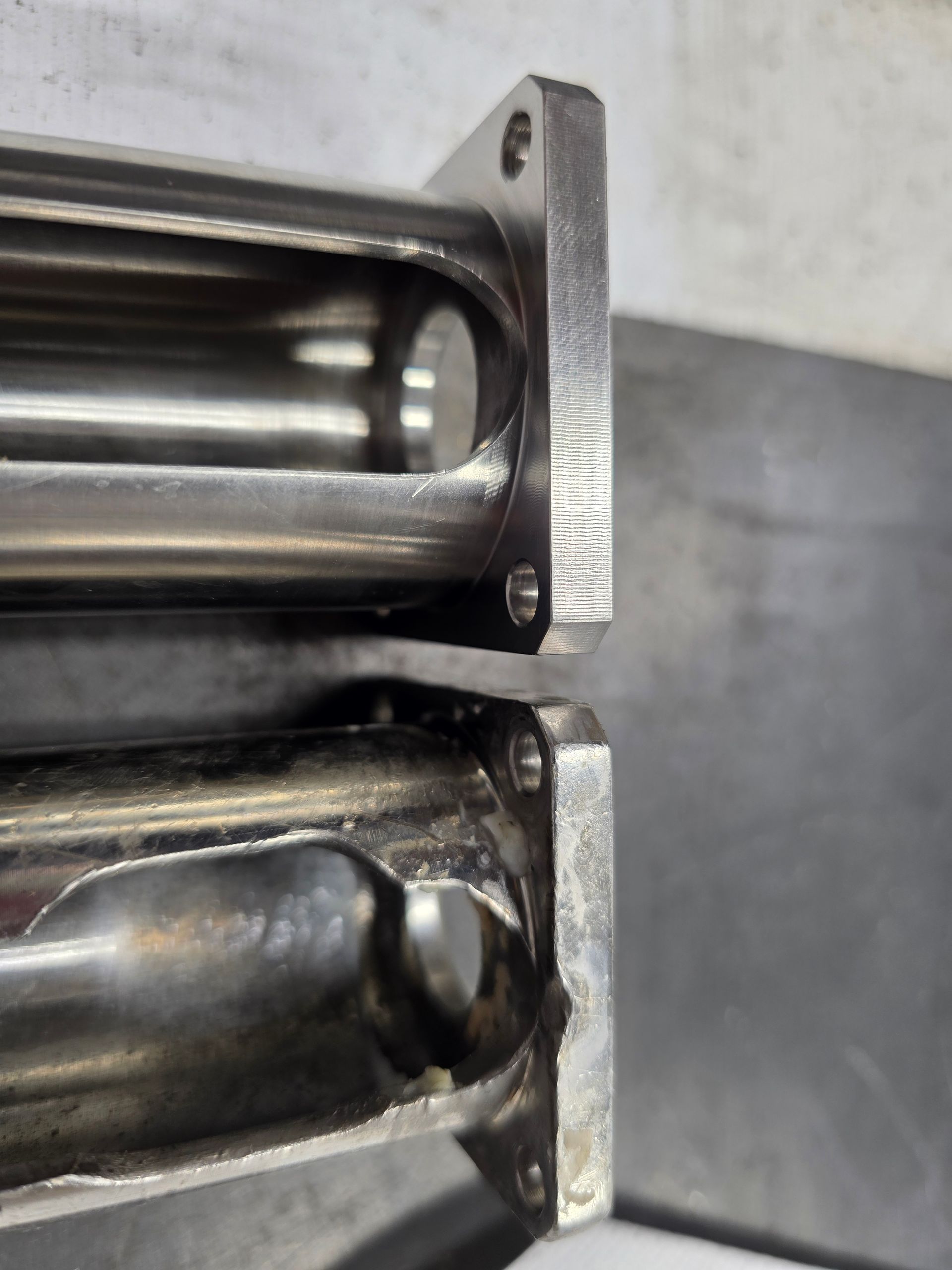 Close-up of two shiny metal pipe sections joined by flanges, with dark residue inside.