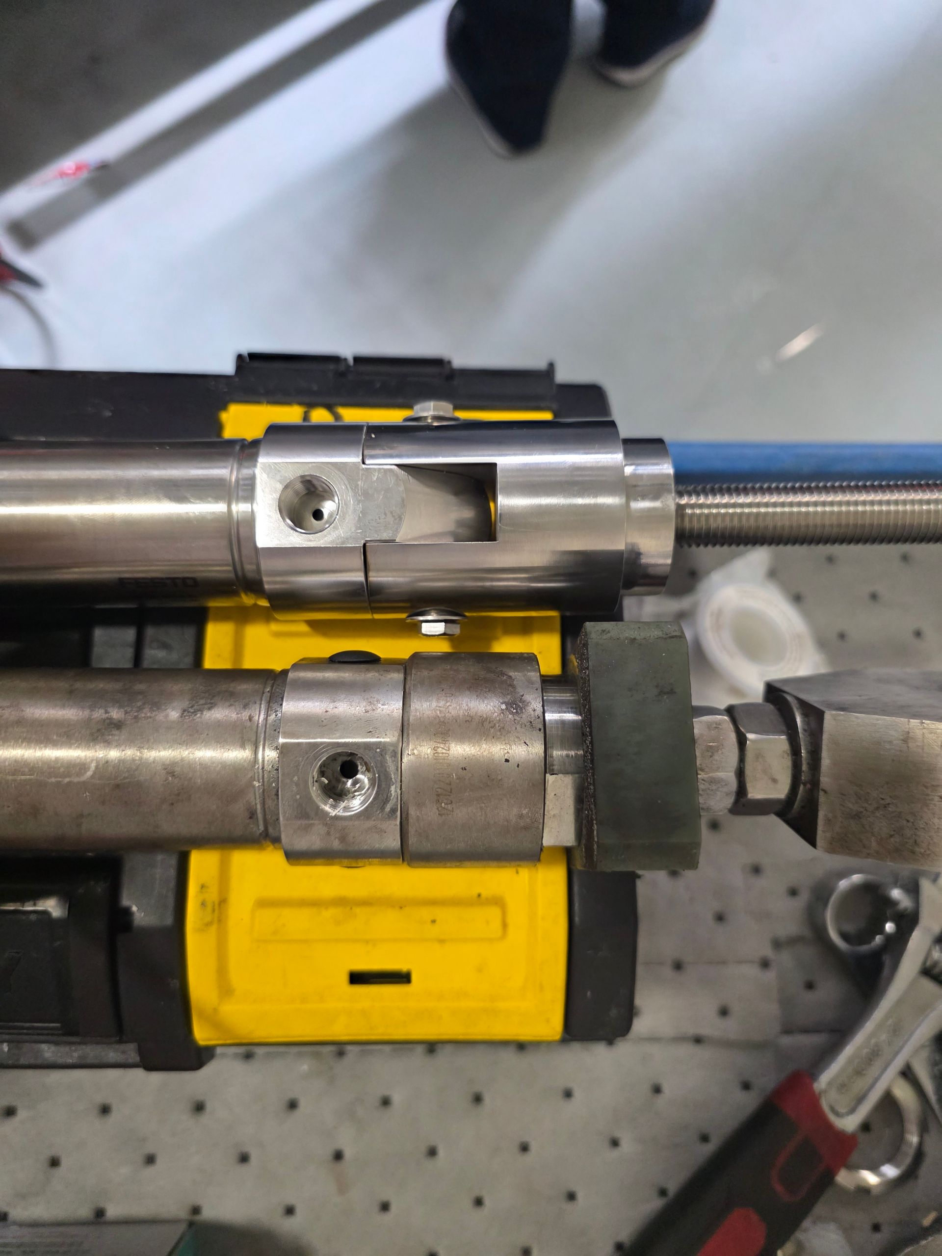 Two metal cylinders with yellow clamps on a workbench, shown in close-up.