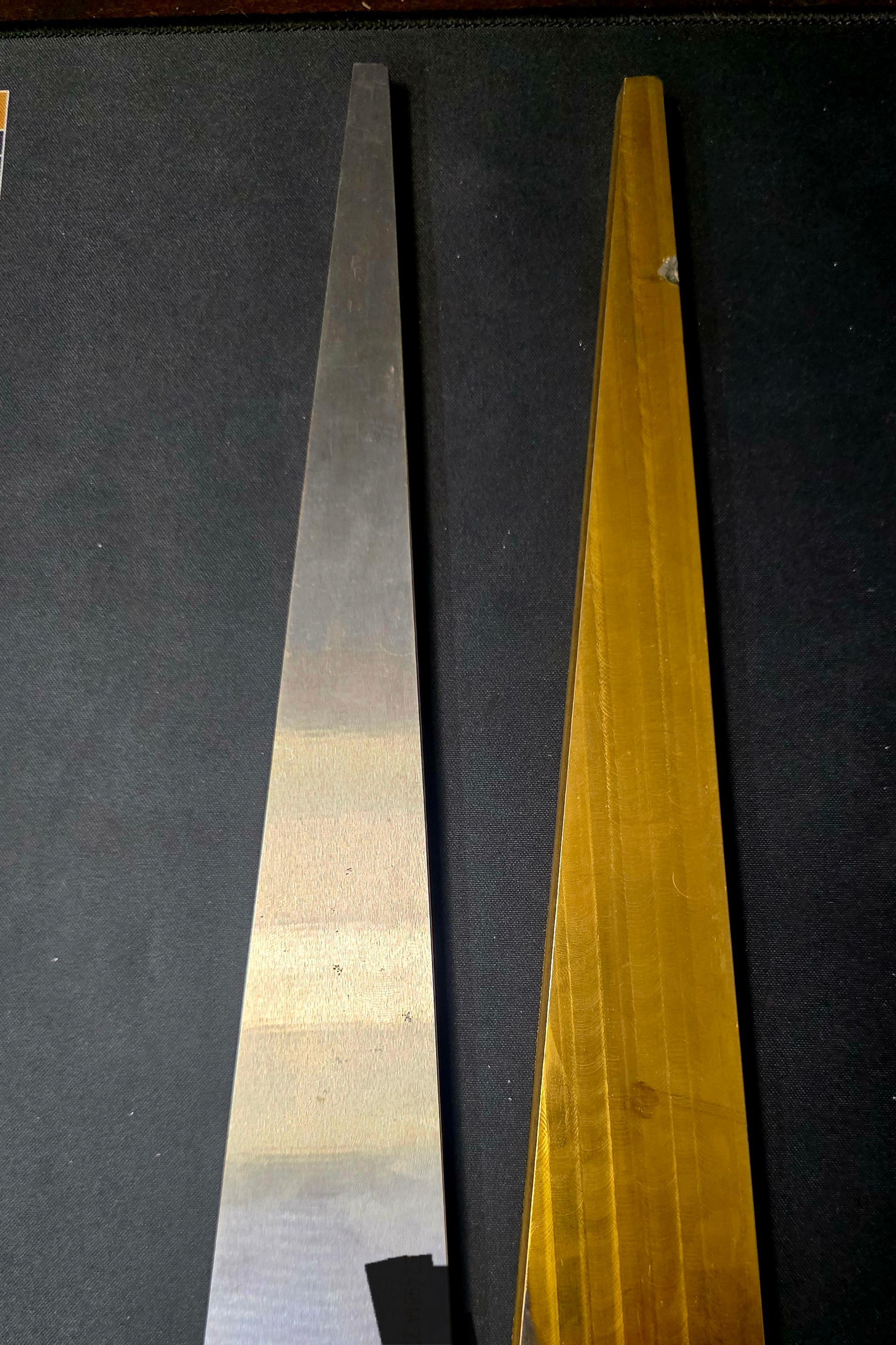 Two long, pointed strips side by side: one silver-gray, one amber, on a dark textured surface