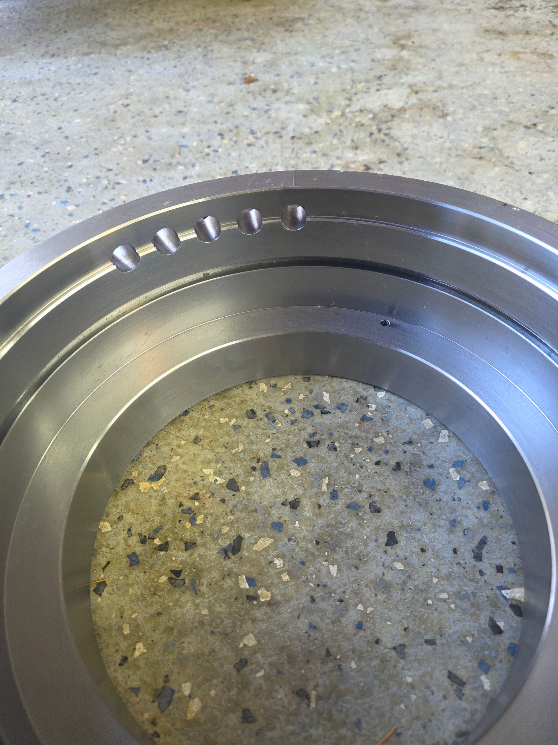 Close-up of a metal circular dish with a speckled, worn interior on a countertop