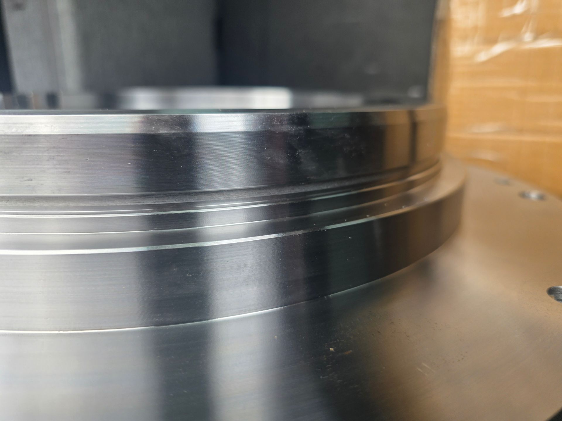 Close-up of a shiny metal cylindrical machine part with a bolted base and reflective surface