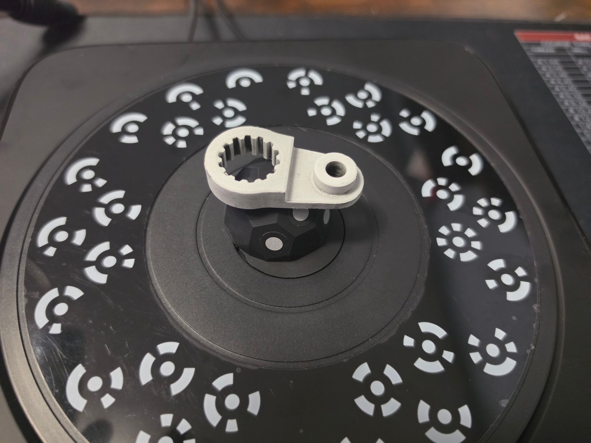 Close-up of a black turntable platter with a small metal adapter mounted at the center.