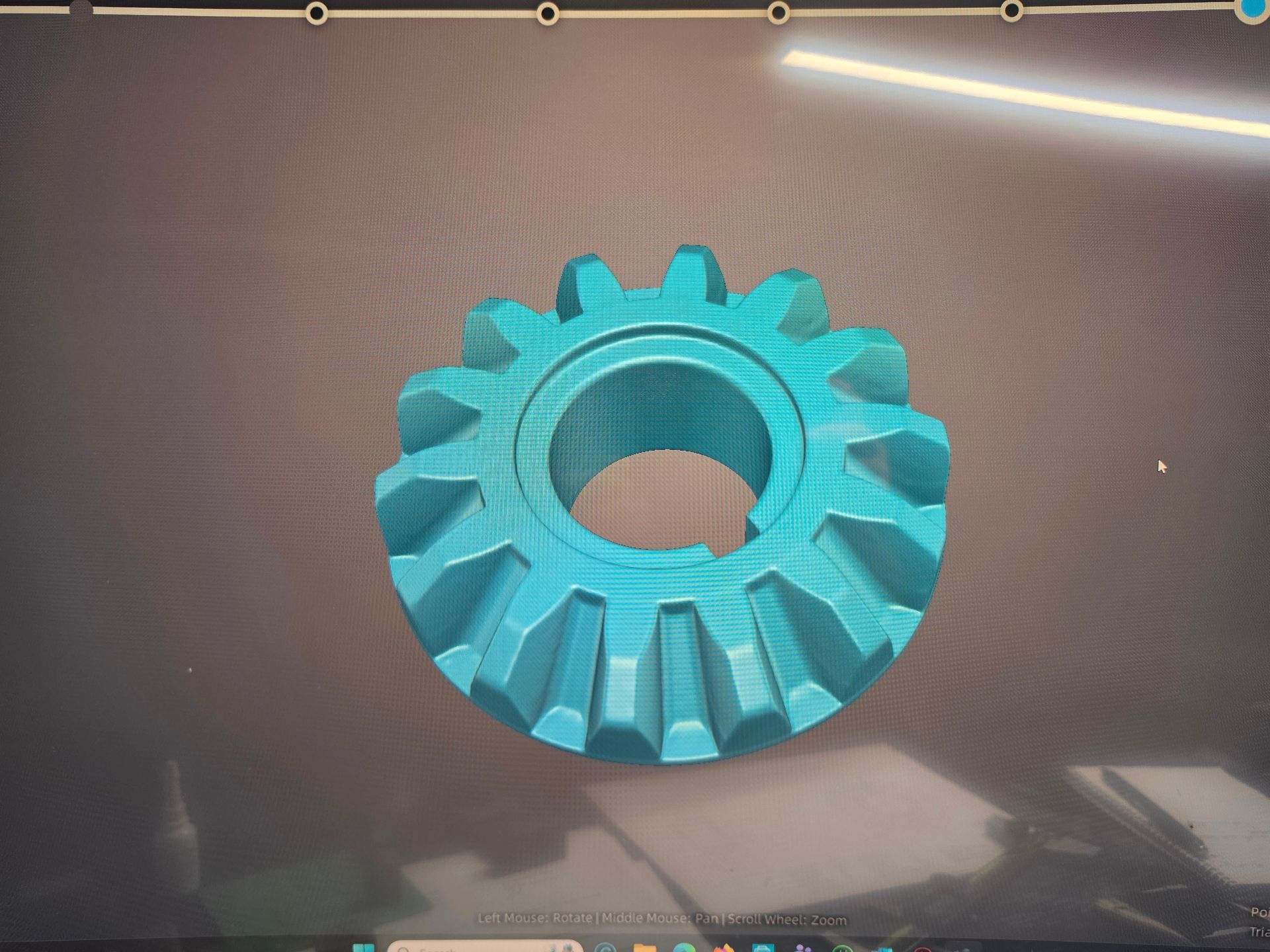 Turquoise gear-shaped 3D-printed ring on a dark surface, viewed from above