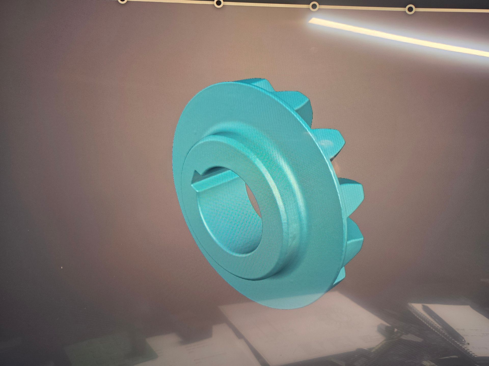 Turquoise 3D gear-like ring with raised tabs, displayed on a soft beige background.