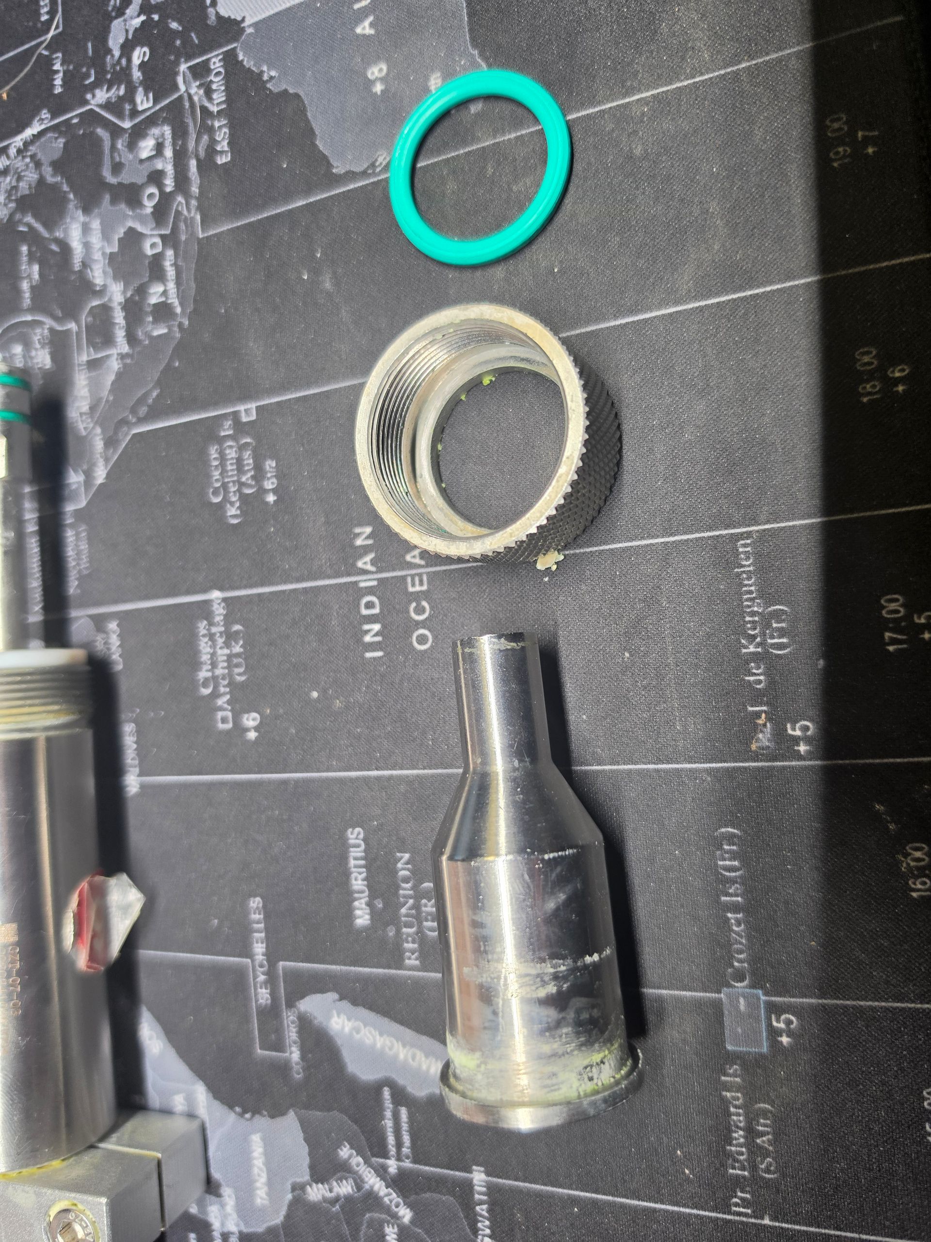 Scattered small metal parts and rings on a dark cutting mat with white grid lines.