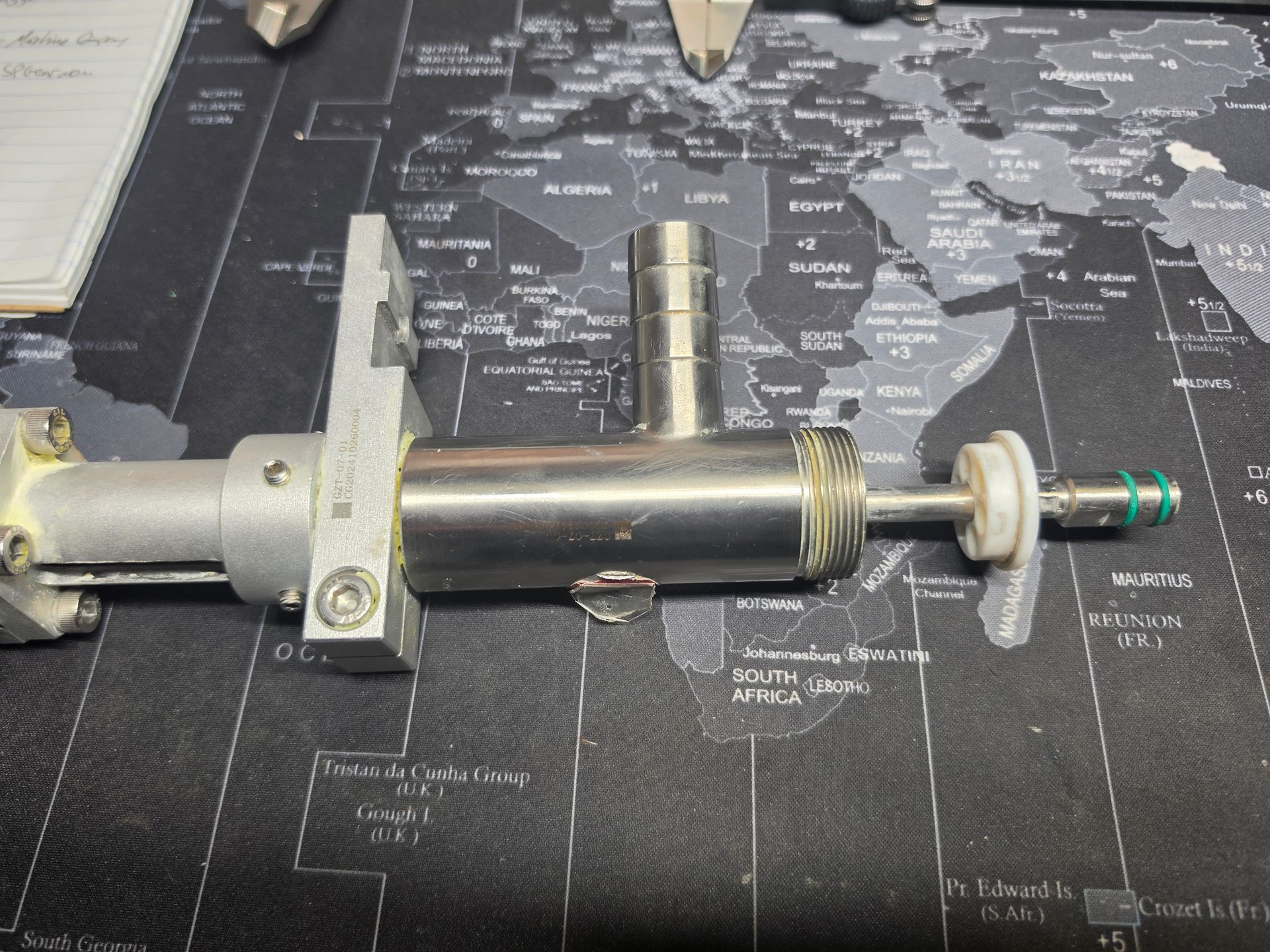 Close-up of a metal mechanical component laid on a dark world map surface.