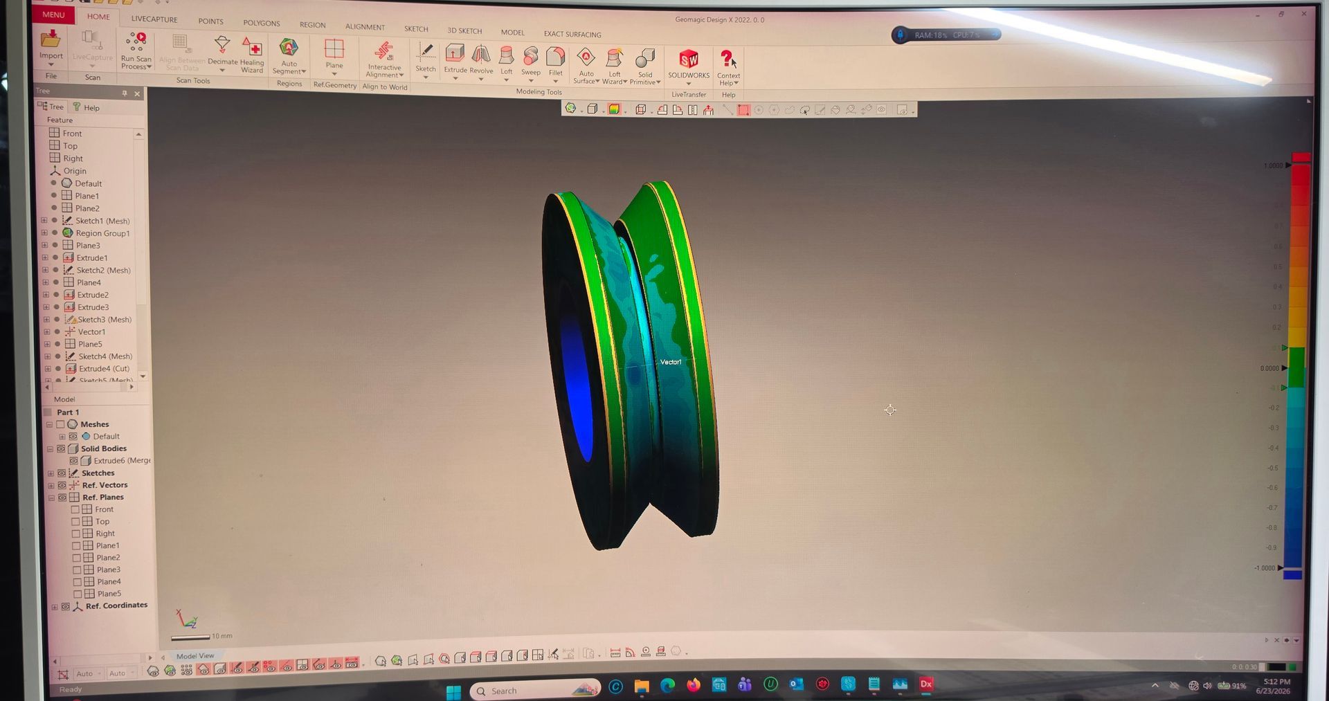 Computer screen showing a 3D modeling program with a green-and-blue mechanical part model on a gray workspace