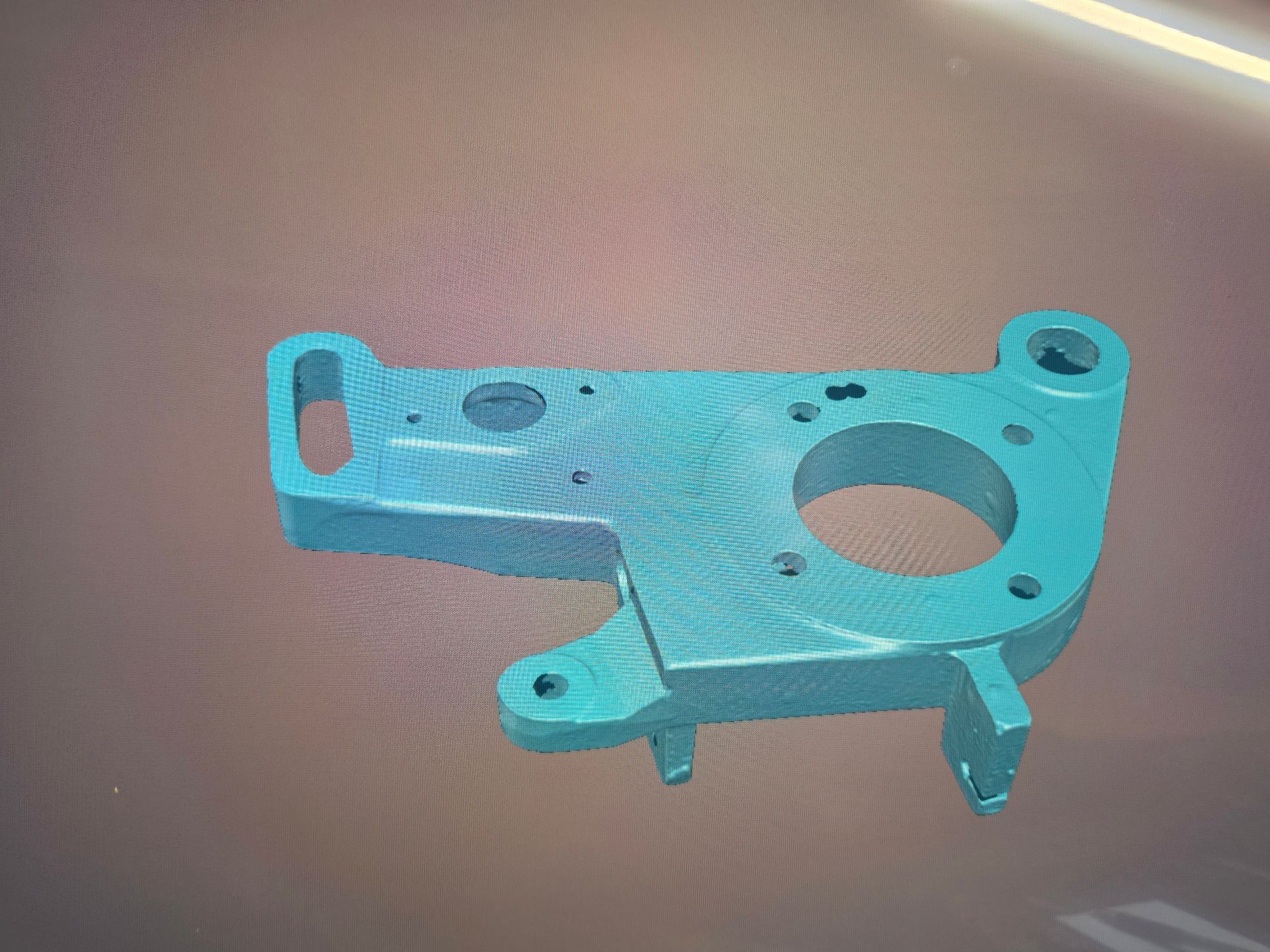 Blue metal mechanical bracket with mounting holes and a large circular cutout on a tabletop.