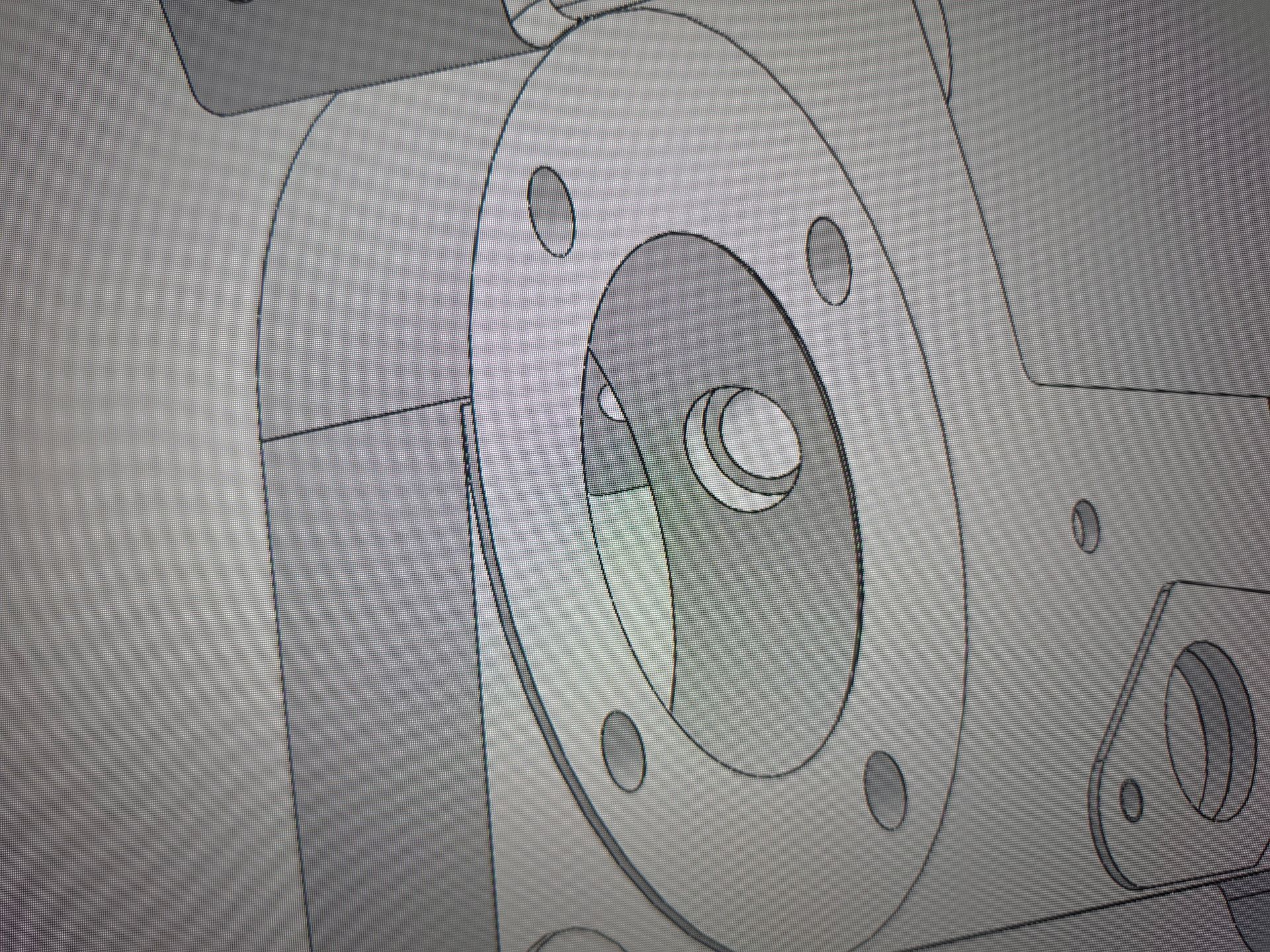 Close-up of a gray metal mechanical flange with bolt holes and a central opening.