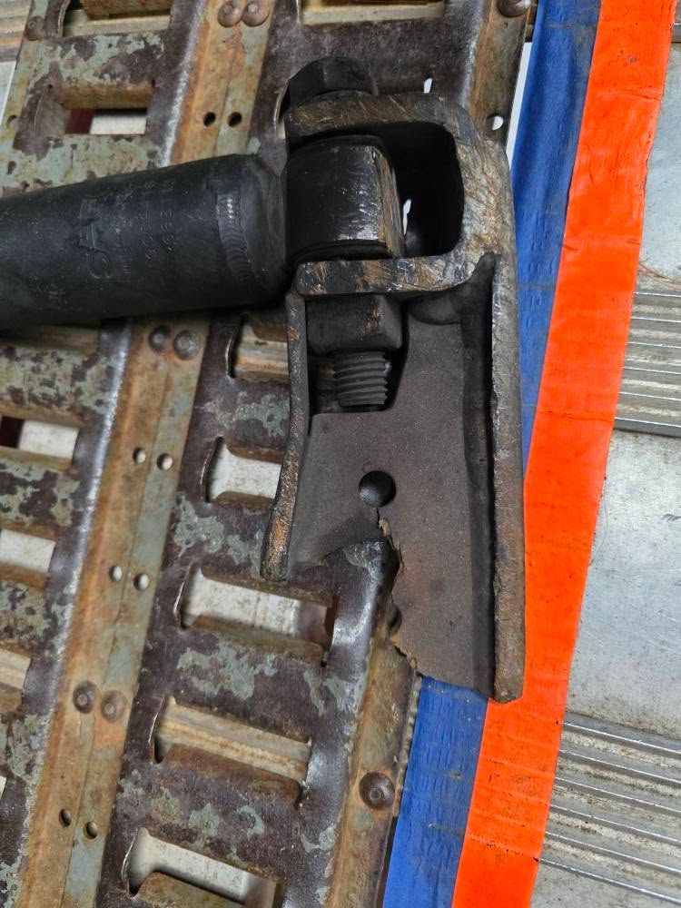 Rusty metal cargo track with a black lever attached by a bolt and nut.