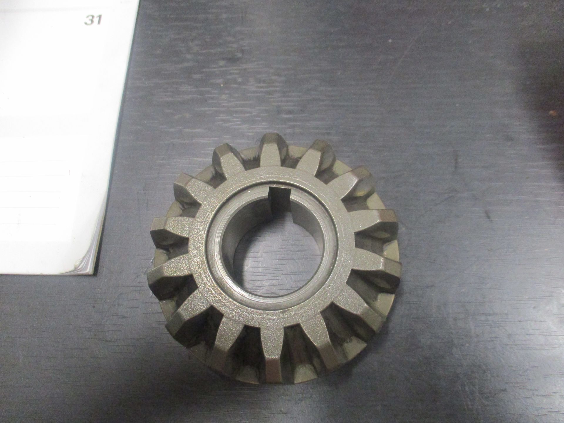 Metal gear sprocket with central hole on a dark tabletop