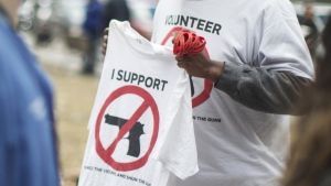 Physicians and health workers protesting in Toronto, walk past a volunteer from the anti-gun group 'Silence the Violence and Shun the Guns,'