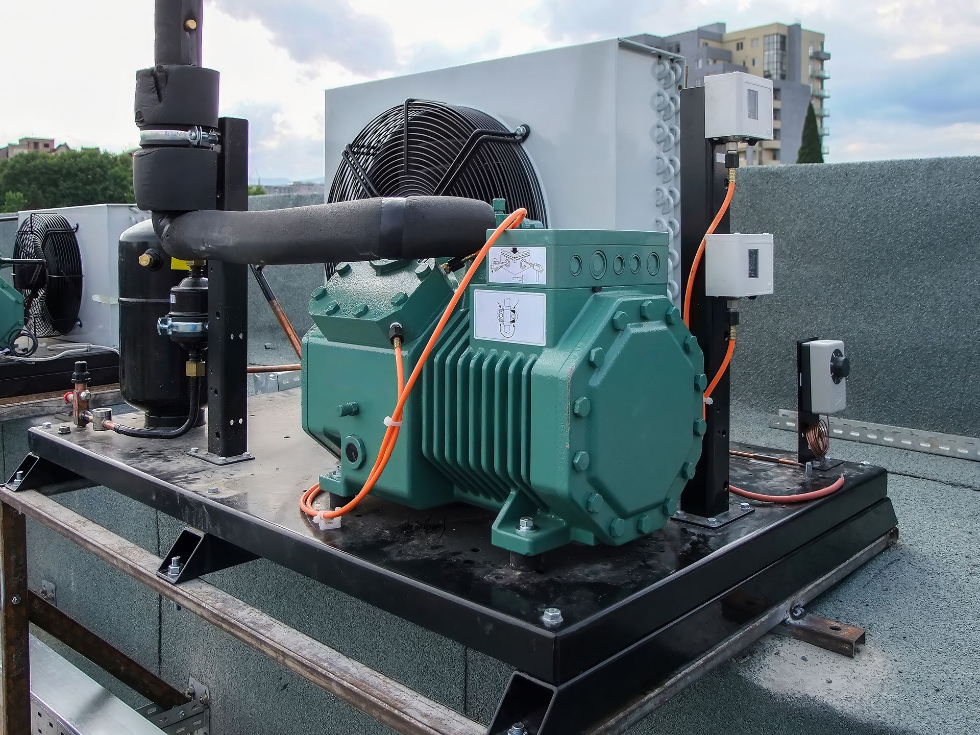 Industrial compressor unit on a rooftop platform with green machinery, pipes, and fans under cloudy sky Industrial compressor unit on a rooftop platform with green machinery, pipes, and fans under cloudy sky