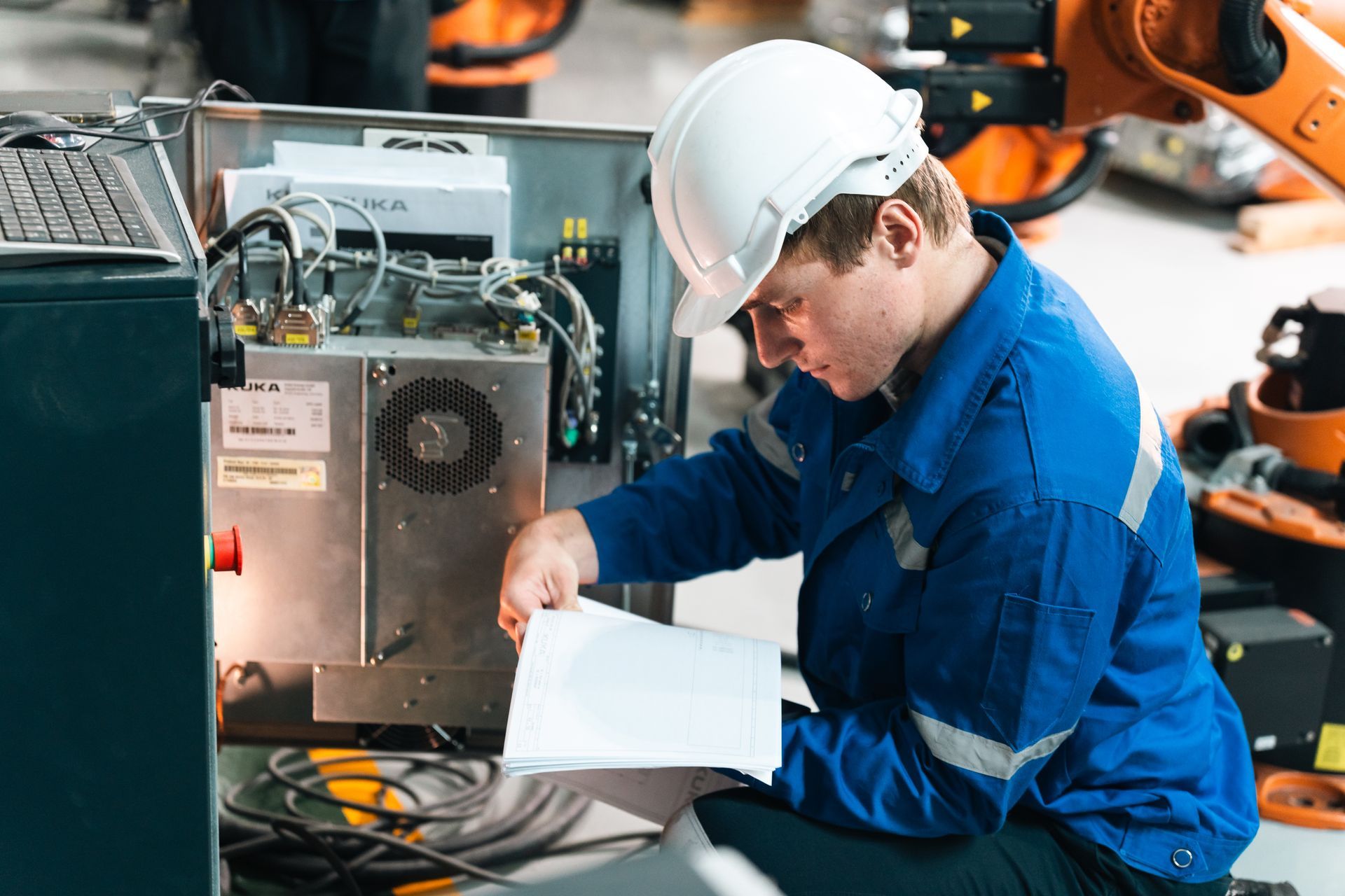 Technician in blue coveralls and white hard hat inspecting machinery in an industrial setting Technician in blue coveralls and white hard hat inspecting machinery in an industrial setting