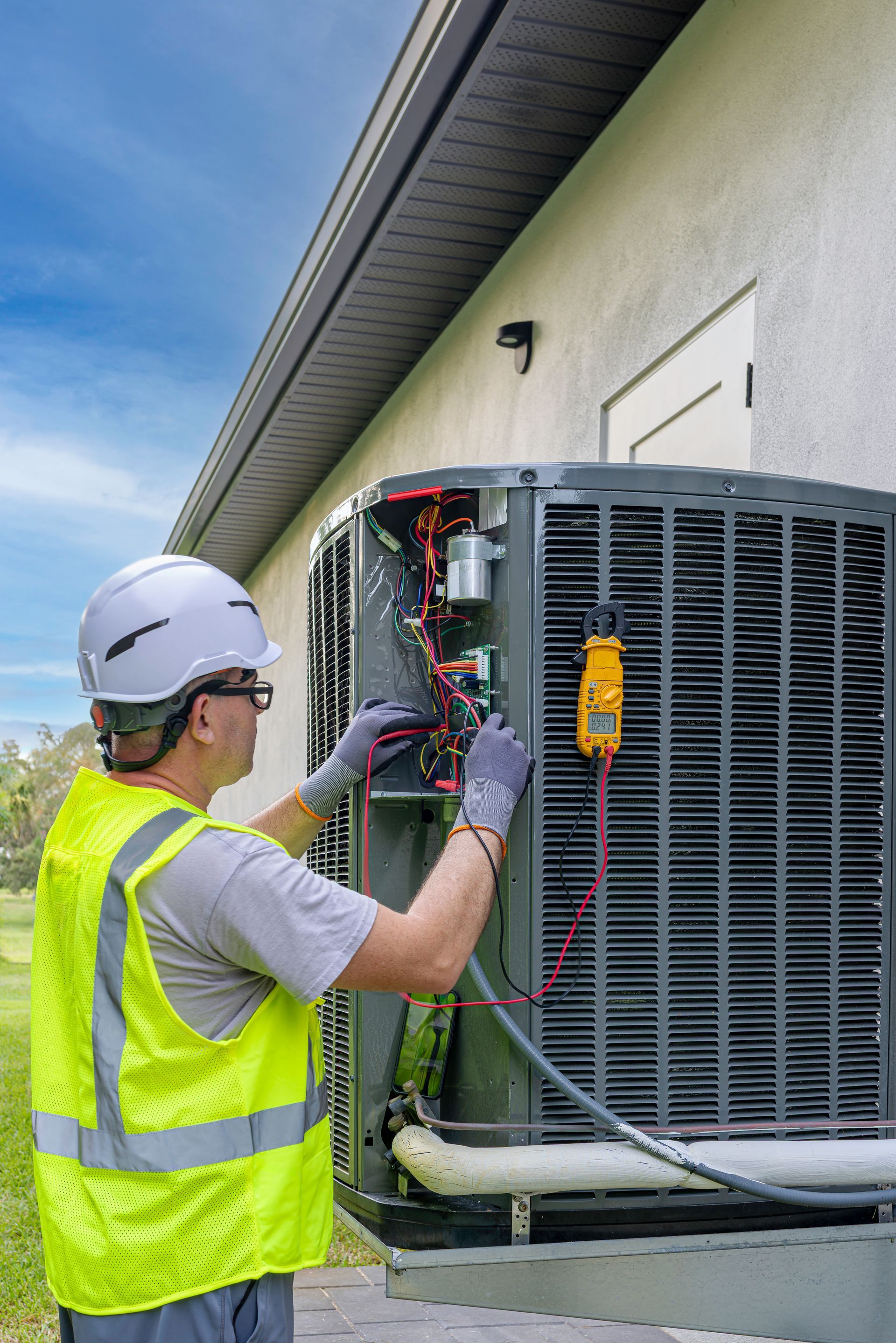 Licensed HVAC contractor testing condenser unit electrical components with meter.