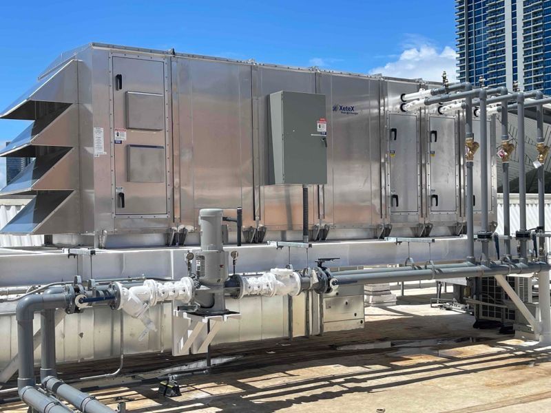 Industrial rooftop HVAC unit under a bright blue sky with clouds