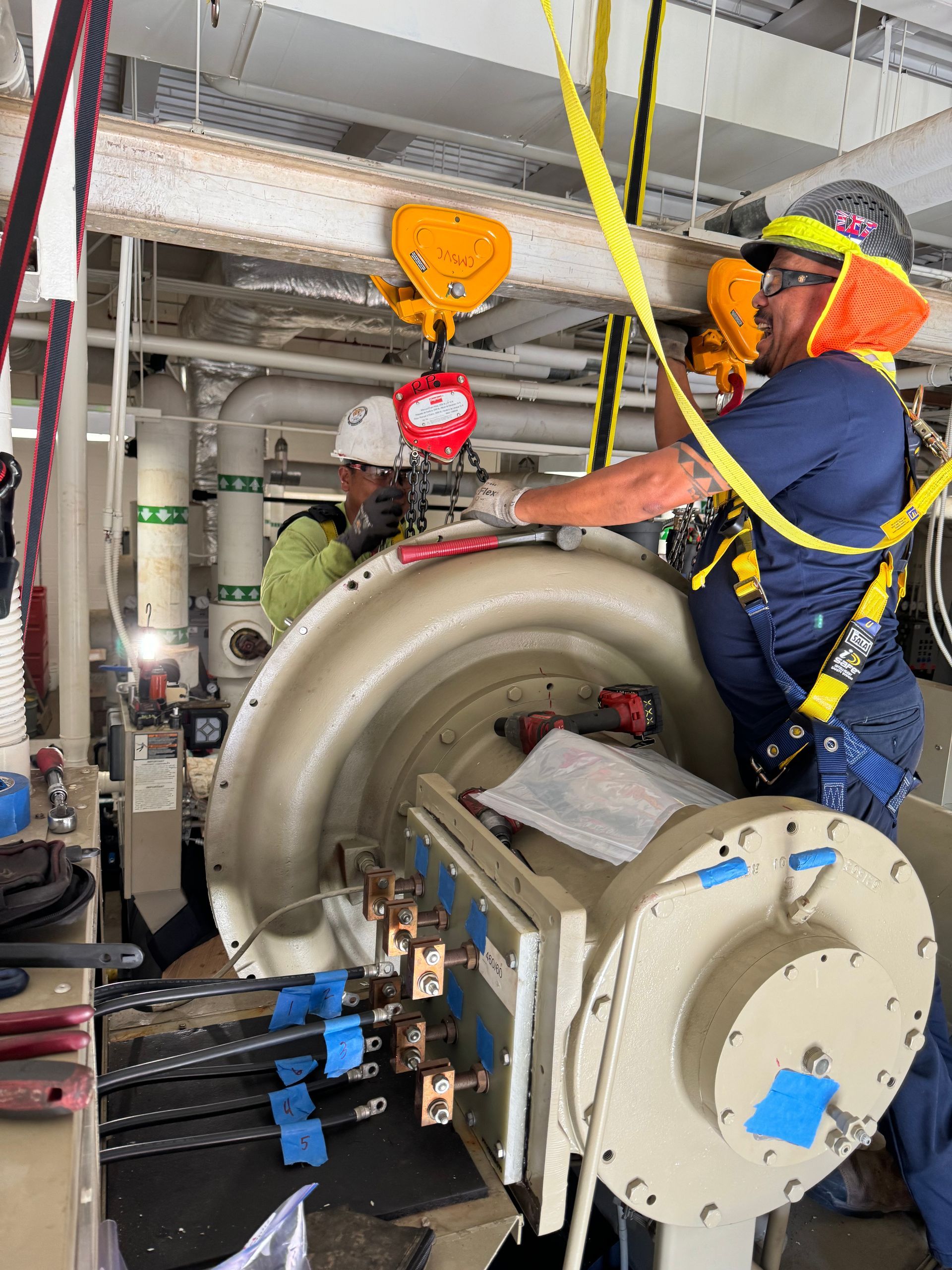 Industrial plant interior with large metal pipes, valves, and equipment under a high ceiling