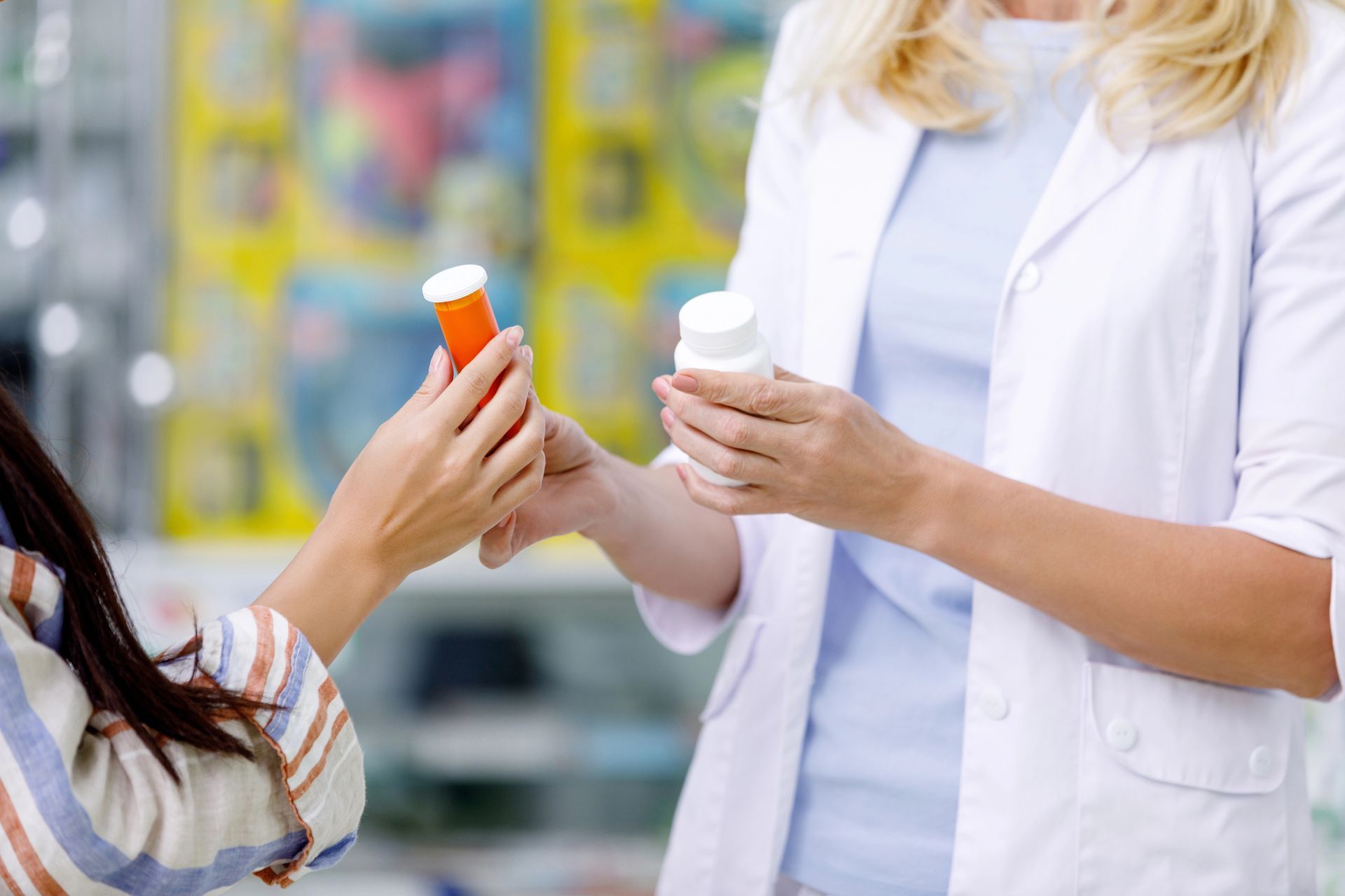 Una mujer le está dando un frasco de pastillas a un farmacéutico en una farmacia.