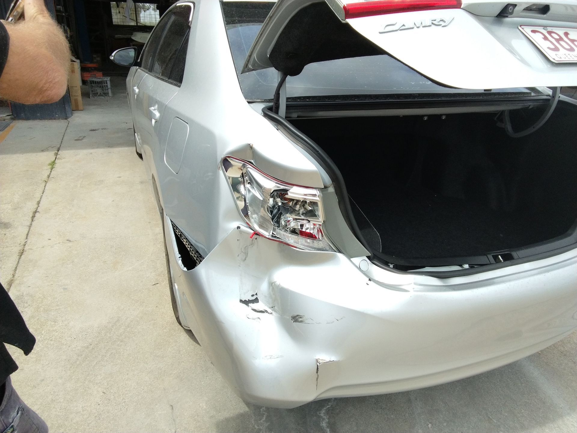 A man is spray painting a blue car in a garage — Proserpine Smash Repairs & Restorations In Proserpine, QLD