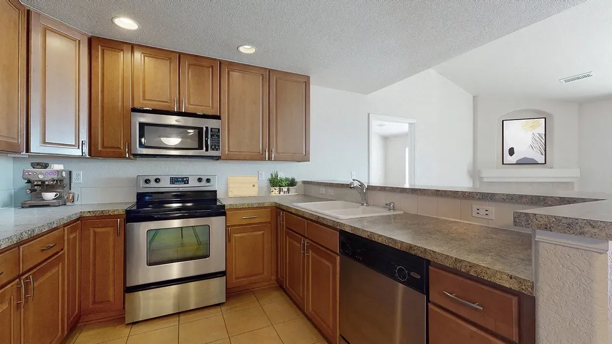 Kitchen with wood cabinets, stainless steel appliances including oven, microwave, and dishwasher, and a double sink.