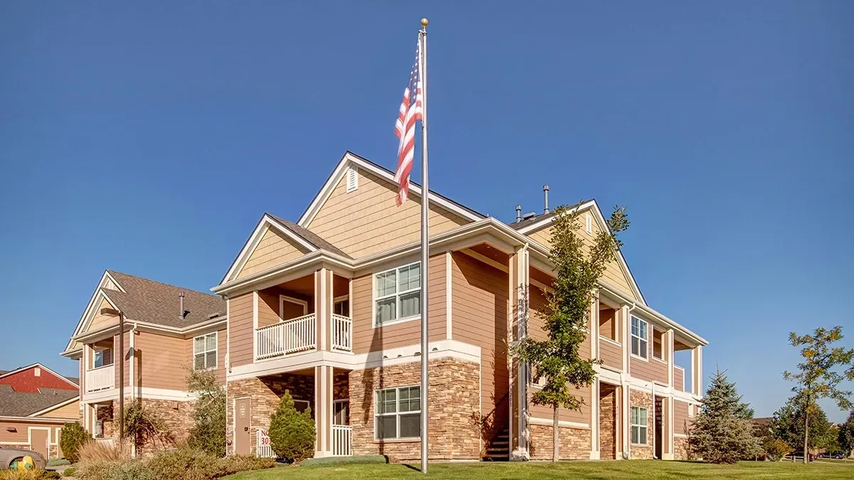 Exterior view of apartment buildings with an American flag flying.