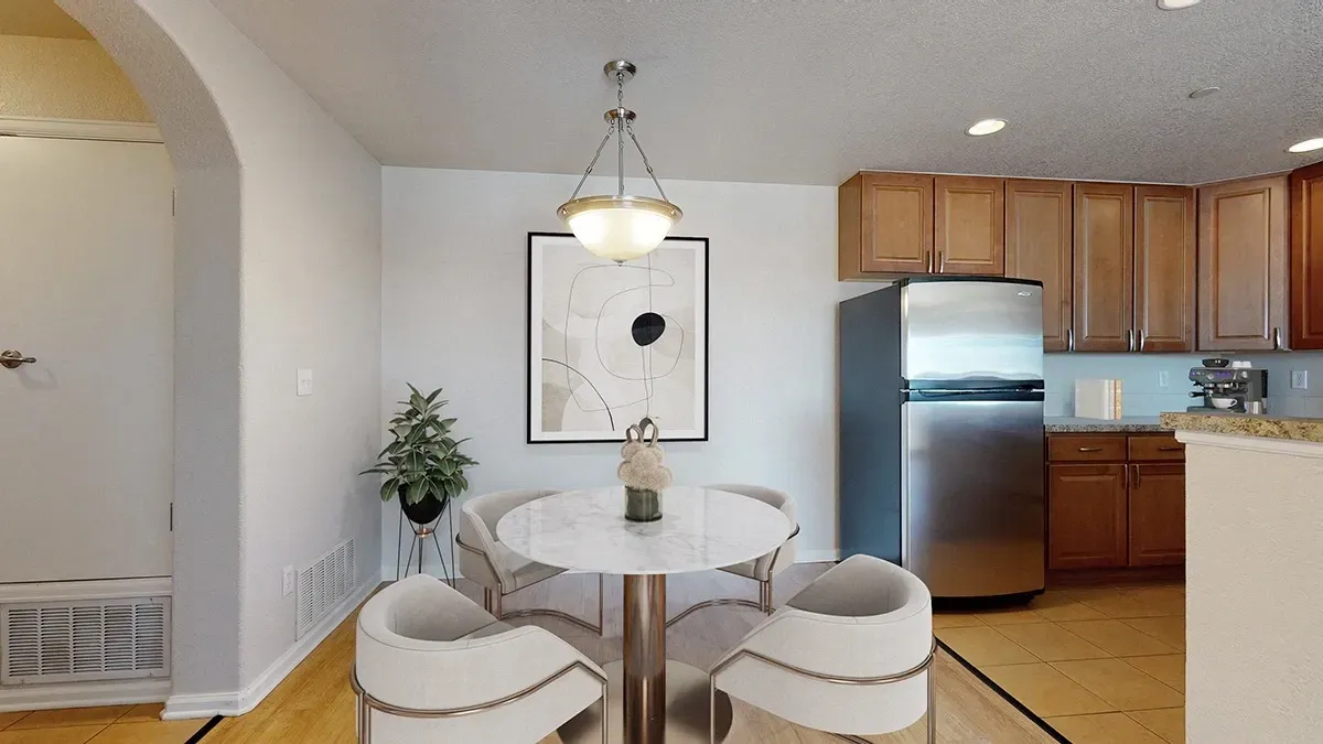 Dining area with table and chairs next to a kitchen with stainless steel appliances.