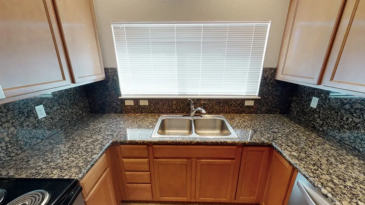 Kitchen sink and granite countertops with window blinds