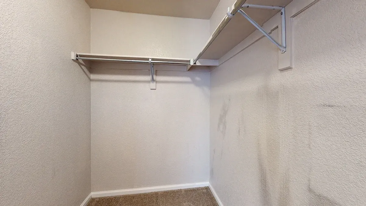 Empty walk-in closet with shelf and hanging rod.