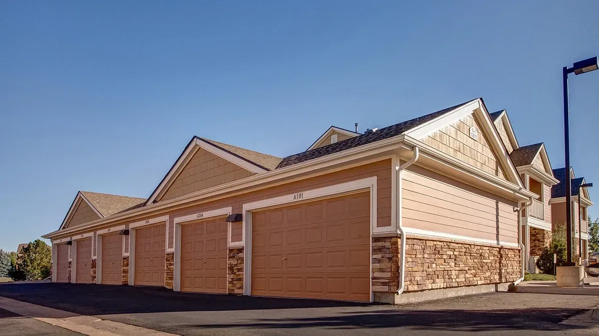Exterior view of apartment garages with stone accents and beige siding.