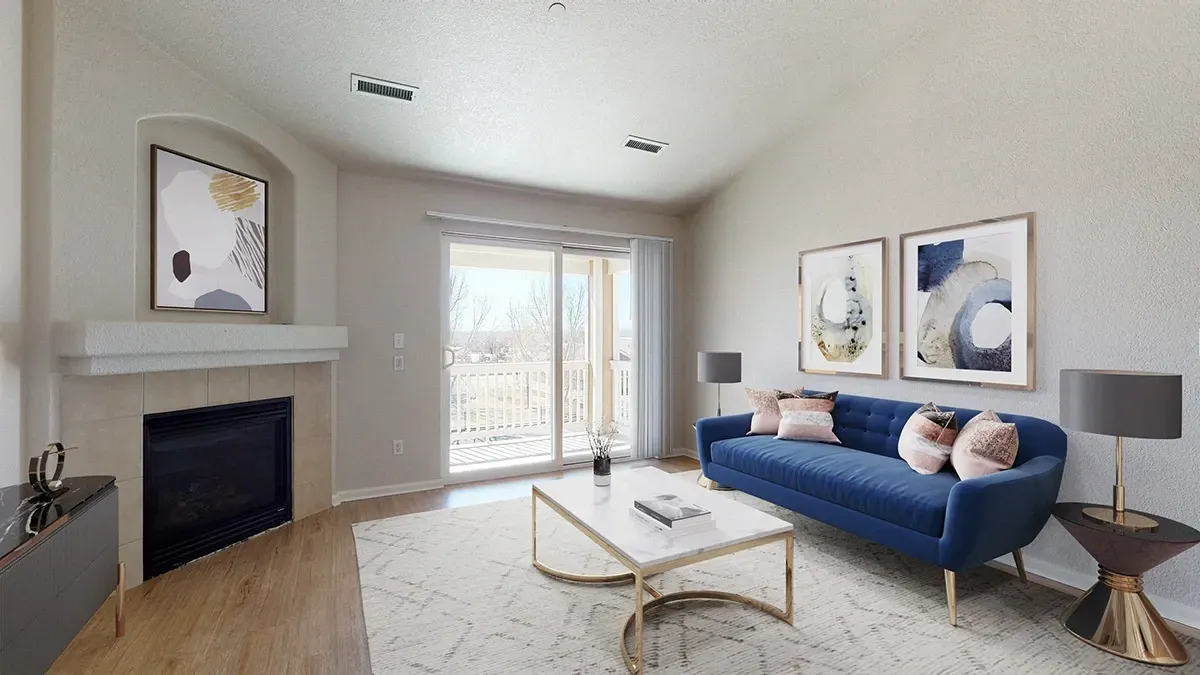 Living room with a blue sofa, coffee table, fireplace, and balcony access.