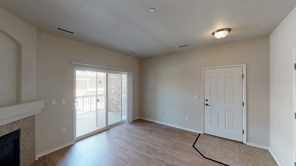 Living room with fireplace and sliding glass door to balcony, interior door and tiled entryway.