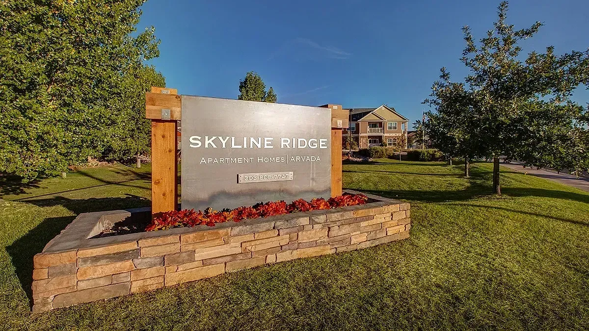 Skyline Ridge entrance sign in a landscaped grassy area with brick planter and trees