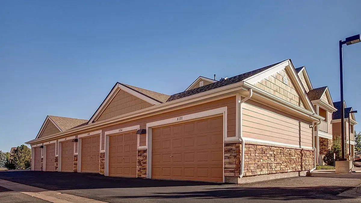 Row of beige brick townhouses with brown garage doors under a clear blue sky