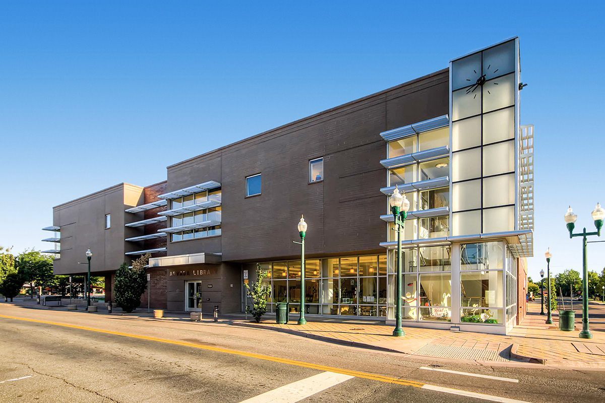 Modern apartment building exterior with balconies and glass stairwell at sunset